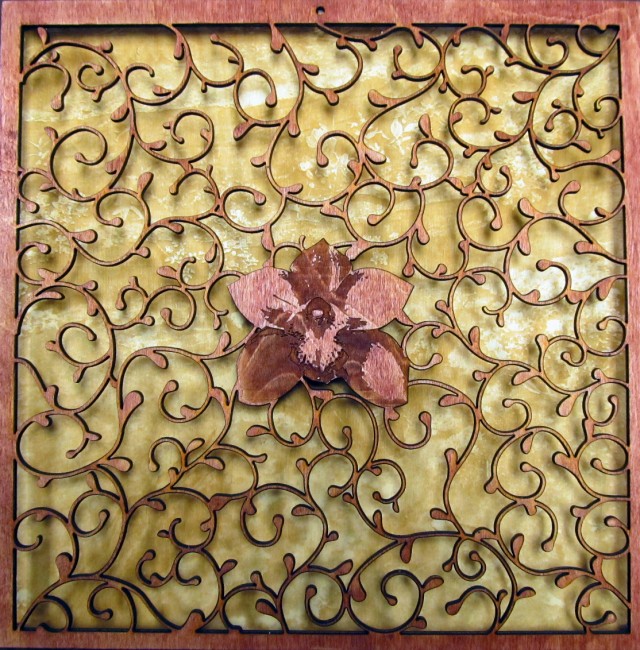 The picture consists of a laser-cut vine motif with an orchid laser-etched in the center, raised a half inch above a laser-etched picture of a creek with large rocks.