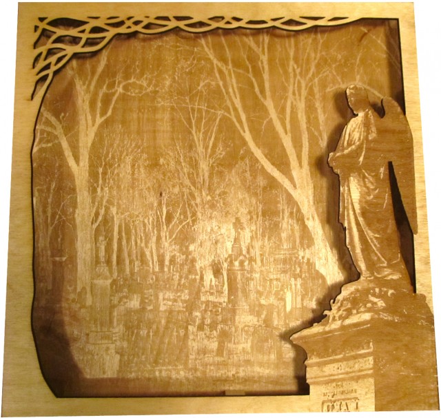 A laser cut piece, one stacked on top of the other for depth.  The top piece is a cut out featuring an angelic grave stone and the back piece is a picture of a graveyard with some well defined trees.